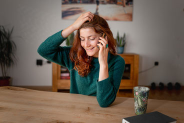 Frau im telefonischen Gespräch zu Hause